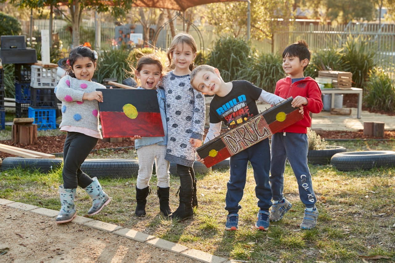 Children holding artwork in a playground.